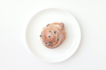 Sweet cinnamon roll with sour cream at a round plate isolated at white background. Pastry image.