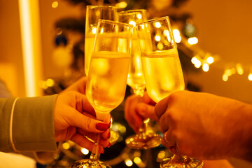 Female and male hands holding glasses with champagne and clicking them. People make festive toast...