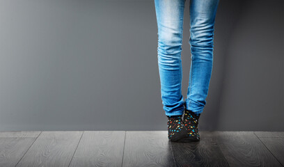 Socks, jeans and legs of person in studio with stylish clothes on wall, mockup space or grey background. Trendy, edgy and fashionista in modern outfit, design or denim with pants on ground and floor - Powered by Adobe