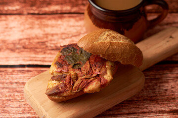 Tamale cake also known as guajolota, it is a tamale placed inside a cake and is a typical preparation of Mexico, placed on a piece of wood in the background a cup of the region