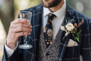 A man with a boutonniere and a glass of champagne in his hand