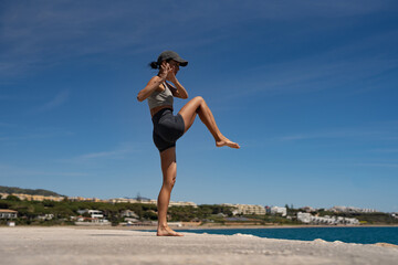 Sultry Brunette Athlete in Sportswear and Baseball Cap Training by the Sea