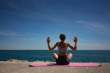 Active Brunette Woman Doing Physical Exercises on Pink Exercise Mat by the Sea