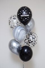 a bunch of black and silver balloons for a man on a white background