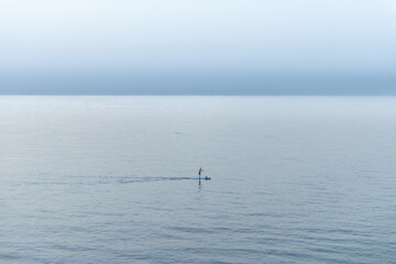 The man paddleboarding on sea early sunset