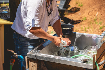 Outdoor clean: man in white shirt and jeans diligently washing dishes in an open-air sink