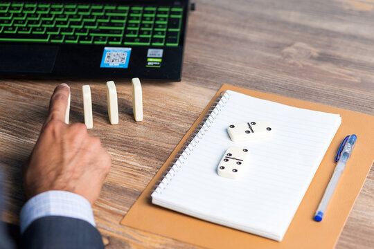 Business man creating domino effect by his hand, business strategy background image, wearing blue suit and red tie