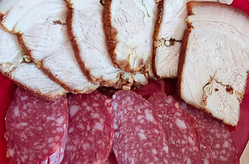 Slices of smoked sausage and boiled pork lie on a plate. Close-up, selective focus.