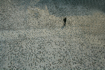 man walking in a square with cobblestones..