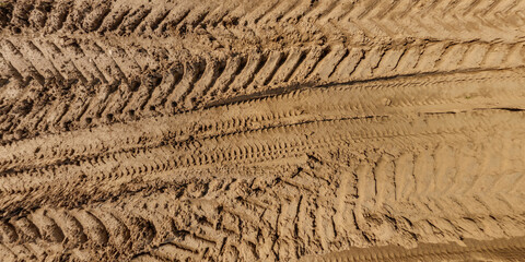 view from above on texture of wet muddy road with tractor tire tracks in countryside