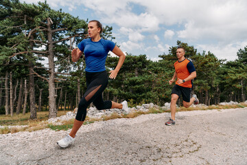 Fototapeta premium A couple dressed in sportswear runs along a scenic road during an early morning workout, enjoying the fresh air and maintaining a healthy lifestyle