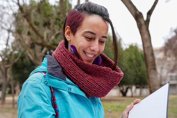 A woman with purple hair is smiling and holding a book