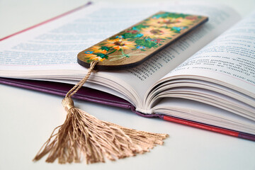 Wooden bookmark with floral design hanging from an open book