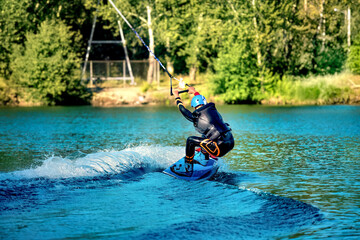 A man wakeboarding on a lake on summer day in a life  jacket. Soft focus. Action blur.