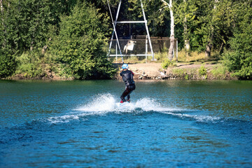 A man wakeboarding on a lake on summer day in a life  jacket. Soft focus. Action blur.