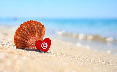 Sandy beach in Tunisia. Tunisia flag in the shape of a heart and a large shell. A wonderful seaside...
