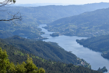 A river winding through a lush, mountainous landscape with dense forests, rolling hills, and open land. Taken from an elevated vantage point.