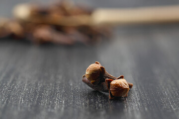 Dry cloves in wooden scoop isolated on white background with clipping path. Top view. Flat lay. selective focus.