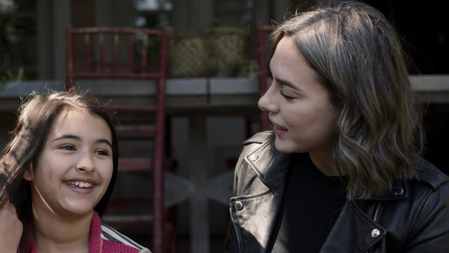 A loving mother hugs her daughter while sitting on stairs outdoors