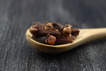 Dry cloves in wooden scoop isolated on white background with clipping path. Top view. Flat lay. selective focus.