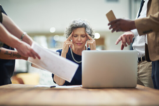 Headache, chaos and business woman in office with documents, report or admin crisis on laptop. Senior manager, boss or CEO with stress, overwhelmed and tired for multitasking or staff time management