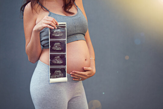 Woman, pregnant and holding belly with sonogram in studio for maternity shoot, album and baby shower. Mother, growth and ultrasound isolated on gray background for gender reveal and surrogacy