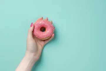 Fotobehang Person Holding Pink Donut With Sprinkles © yganko