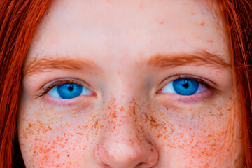 Cropped close-up portrait of red-haired blue-eyed freckled teenage girl