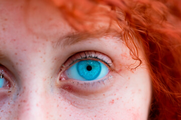 Close-up of bright blue eyes of curly haired redhead girl