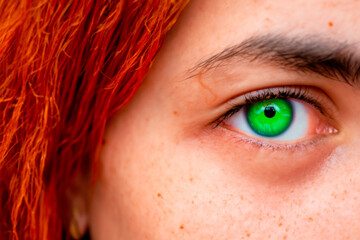 Close-up of bright green eye of young red-haired woman