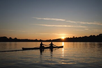 People silhouettes rowing at sunset