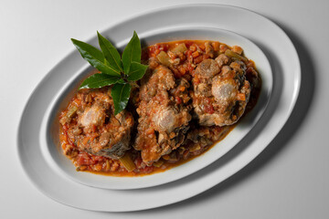 Isolated oval plate with a portion of oxtail stewed vaccinara
