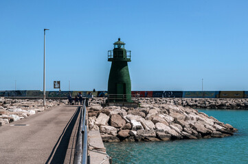 Pier with yachts on the seashore with a lighthouse in Italy