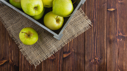 Yellow apples in a crate on a wooden background
