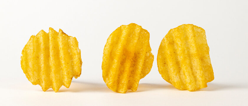 Three wavy chips on a white background with a cropped outline. Corrugated potato chips.