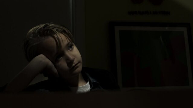 Young boy with a sad expression listens to his parents fighting in the next room