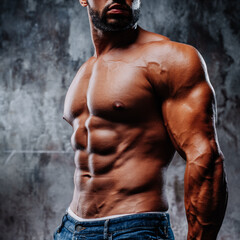 Young strong man bodybuilder on wall background - obrazy, fototapety, plakaty