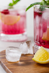 Raspberry cocktail with ice in a glass on a light background