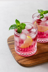 Raspberry cocktail with ice in a glass on a light background