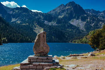 Stone on a pedestal near picturesque lake in the Pyrenees Mountains