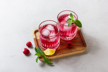 Raspberry cocktail with ice in a glass on a light background