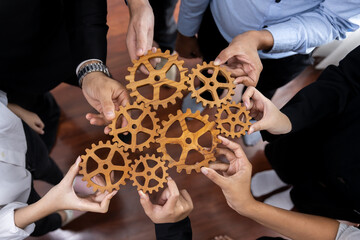 Group of multiracial business people joining gear wheels together as effective unity and productive teamwork concept. Efficient system business team process for solution solving. Meticulous