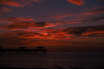 beautiful red sunset in Clearwater Beach Florida, red sunset over the ocean with a pier in the foreground