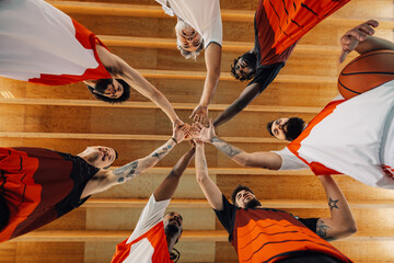 Low angle view of a multiracial basketball team and their coach joining hands