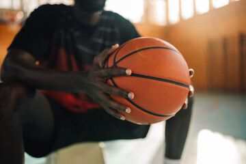 African american basketball player with a ball in his hands sitting on a bench