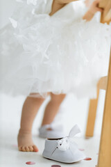 Elegance in Innocence: A Child Barefoot Dance Beside a Pair of White Shoes Amidst Petals