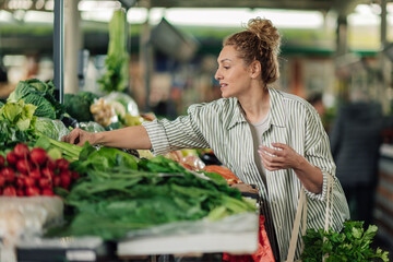 Young woman buying fresh organic groceries at farmer's market. - obrazy, fototapety, plakaty