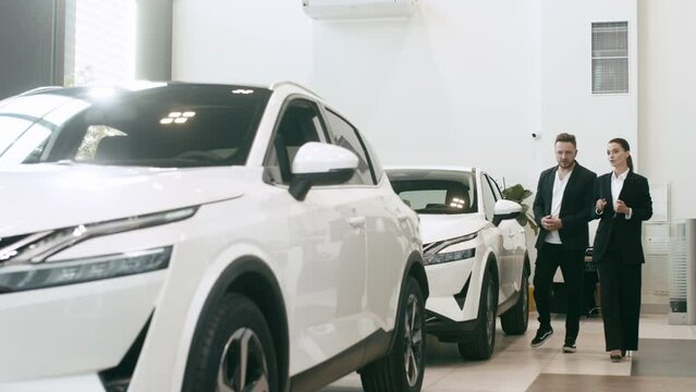 An interested buyer consults with a car dealership manager about the models and characteristics of a modern electric car. Concept of buying and selling a car, deal.