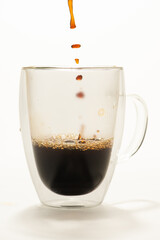 Cup of coffee, glass cup being placed coffee, white background, selective focus.