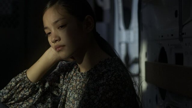 Teenage girl sits in a darkly lit vehicle